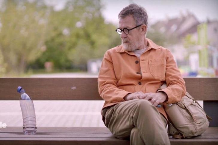 Assis sur un banc, Jamy regarde une bouteille d'eau posée sur sa droite